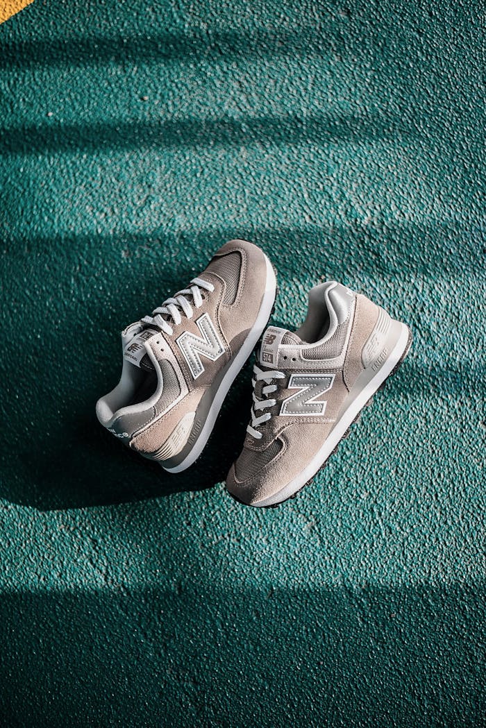 Overhead shot of New Balance sneakers on a teal textured surface under natural light.