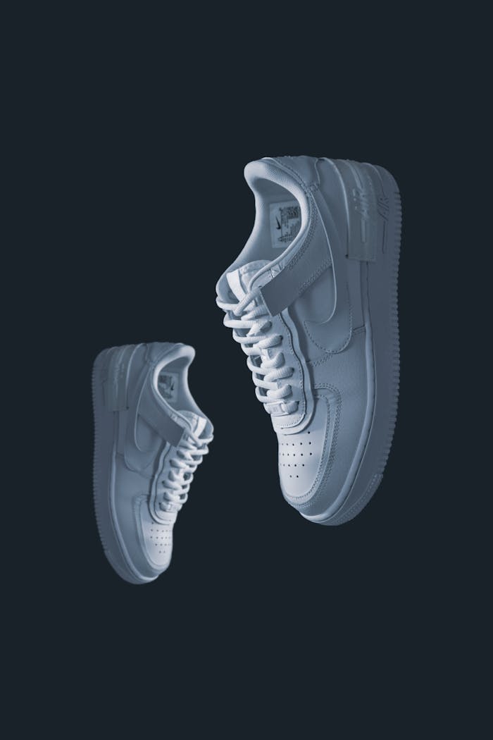 Minimalist studio shot of white sneakers suspended against a dark backdrop.