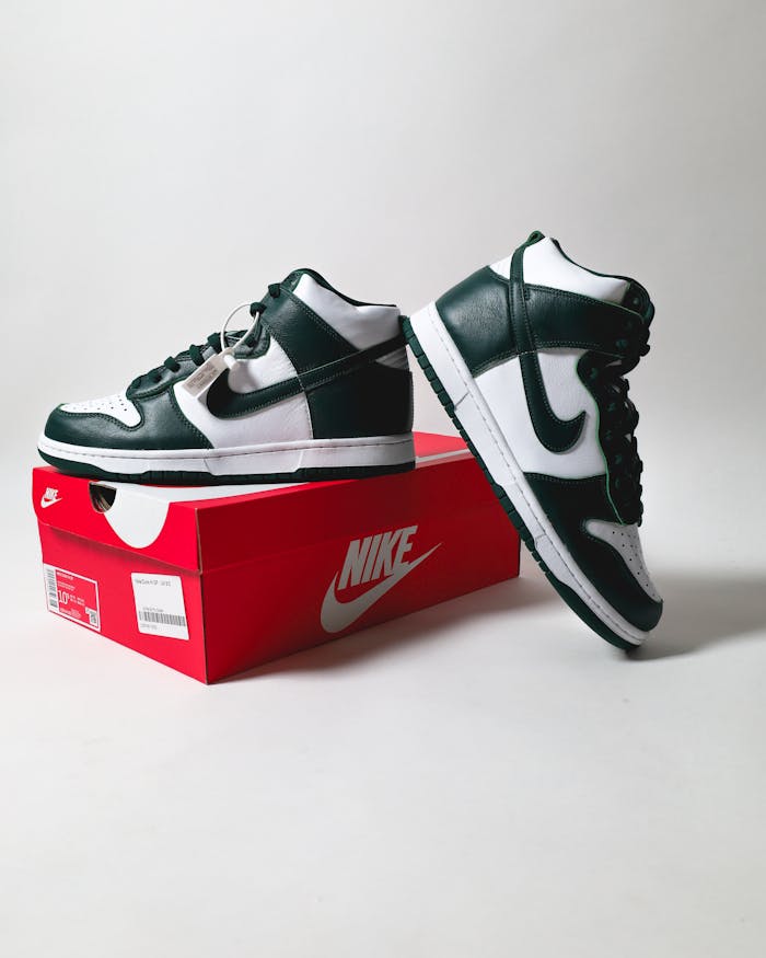 Studio shot of black and white sports shoes displayed on a red shoe box with logo.