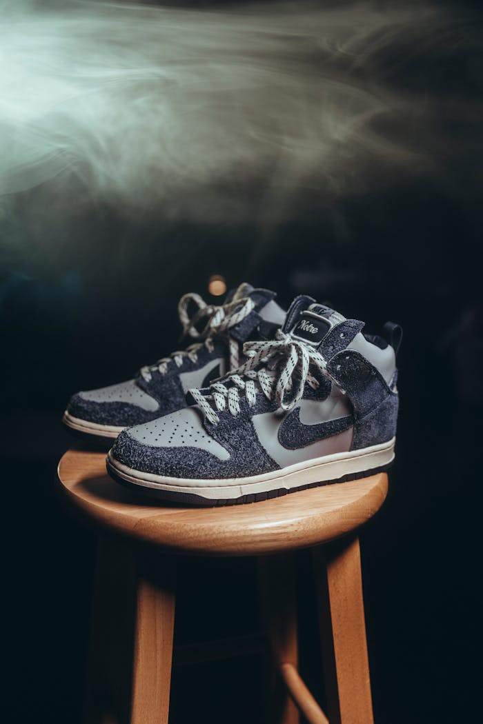 Studio shot of Nike Dunk High sneakers on a wooden stool with atmospheric lighting.